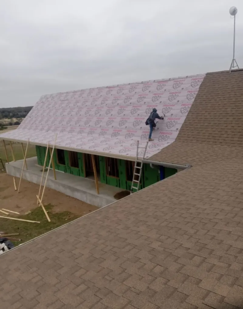 Worker preparing underlayment for a metal roof installation in South Park